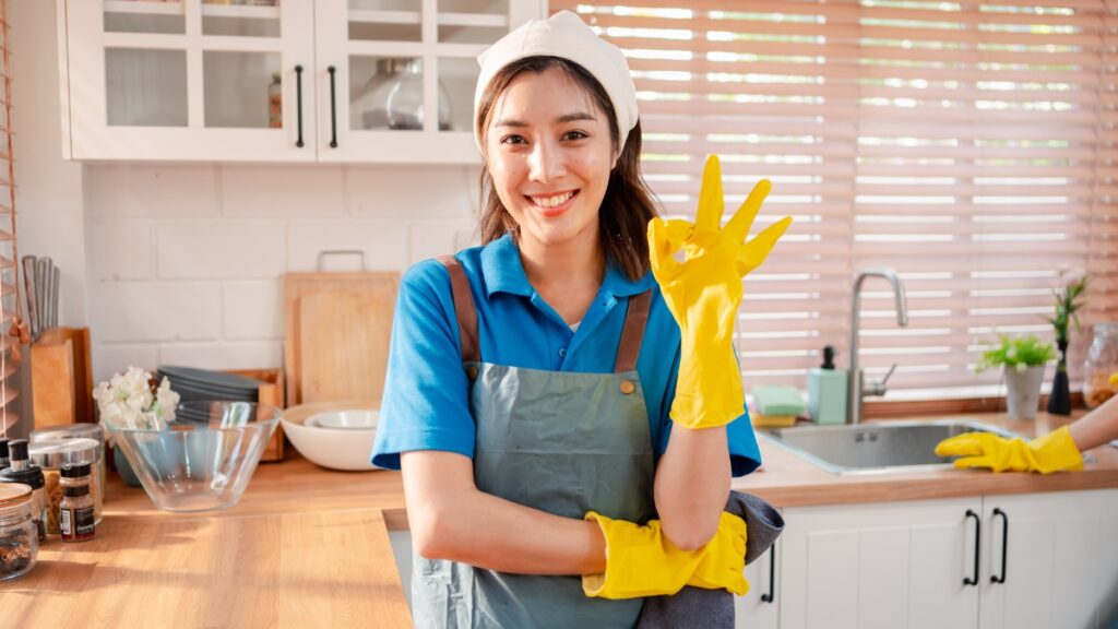Maid service professional standing in a freshly cleaned kitchen after completing detailed house cleaning.