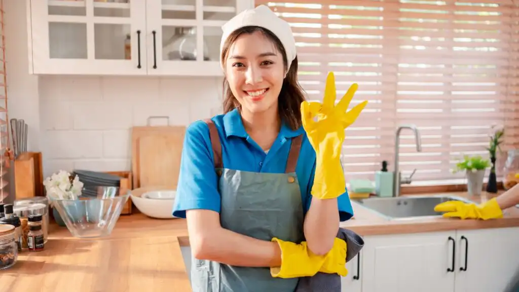 Maid service professional standing in a freshly cleaned kitchen after completing detailed house cleaning.